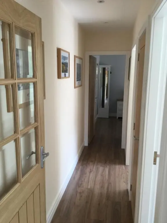 an empty hallway with a door and a hallwayngth at Lesanne Cottage in Inverness