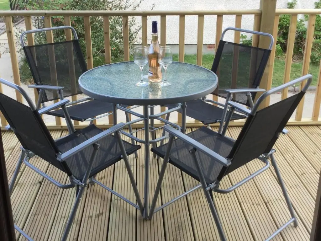 a glass table with two wine glasses on a deck at Lesanne Cottage in Inverness