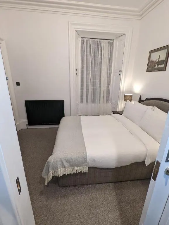 a bedroom with a large bed and a window at Cambeth Lodge Guesthouse in Inverness