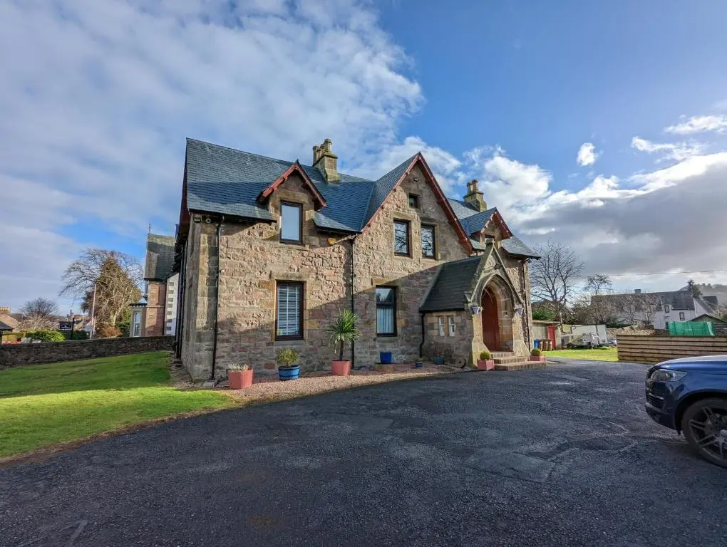 a stone house with a car parked in front of it at Cambeth Lodge Guesthouse in Inverness