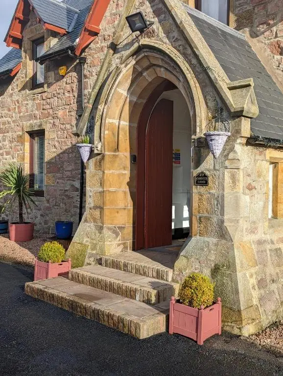 a stone building with stairs leading to a door at Cambeth Lodge Guesthouse in Inverness