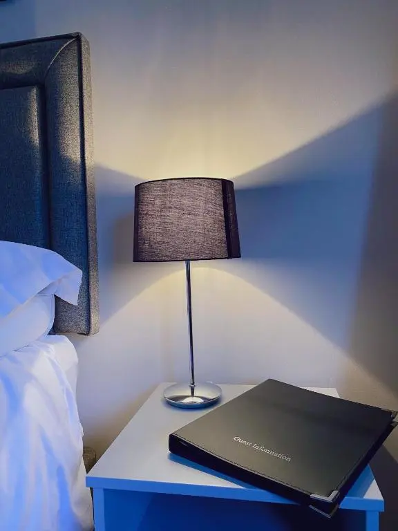 a laptop on a table next to a bed with a lamp at Cairngorm Guest House in Aviemore
