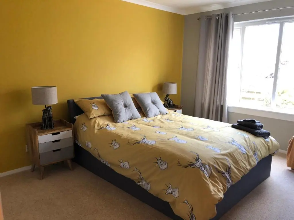 a bedroom with a bed with yellow walls and a window at Linmore in Aviemore