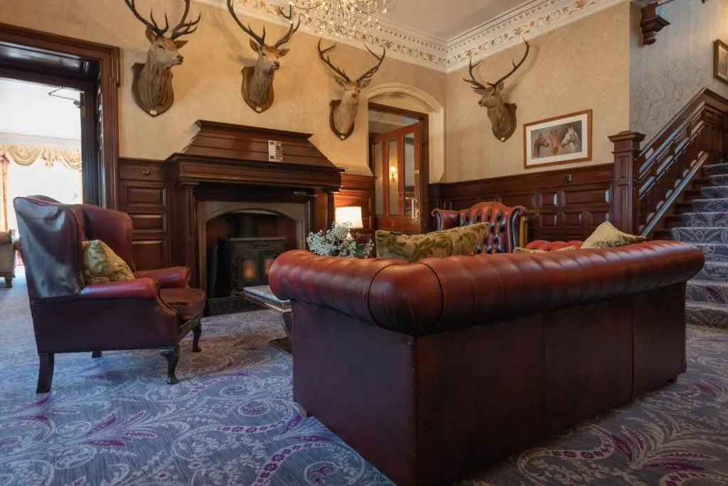 a living room with a leather couch and a fireplace at Ledgowan Lodge Hotel in Achnasheen