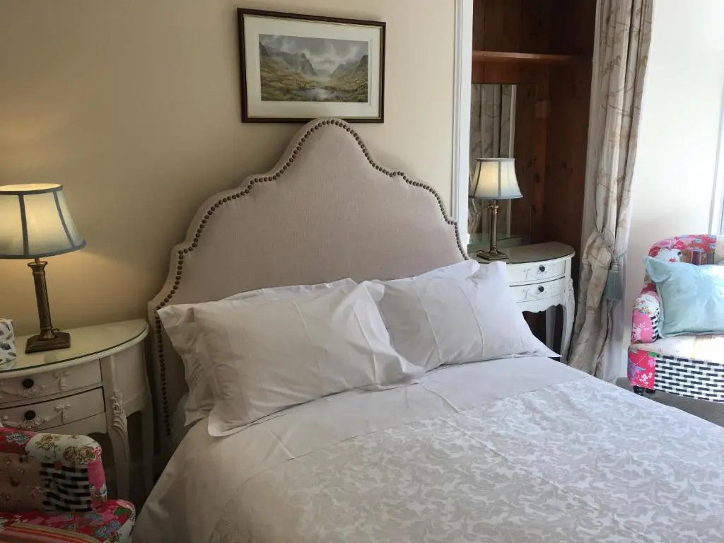 a bedroom with a bed with white sheets and pillows at Ledgowan Lodge Hotel in Achnasheen