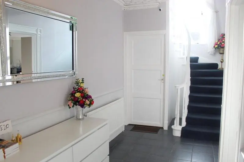 a hallway with a staircase with a mirror and a vase with flowers at Beautiful house on NC500 Route in Wick