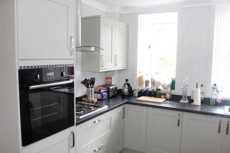 a kitchen with white cabinets and a black stove top oven at Beautiful house on NC500 Route in Wick