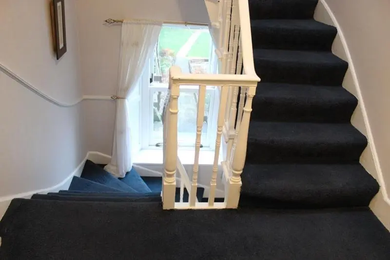a staircase with black carpeting and a white stair case at Beautiful house on NC500 Route in Wick