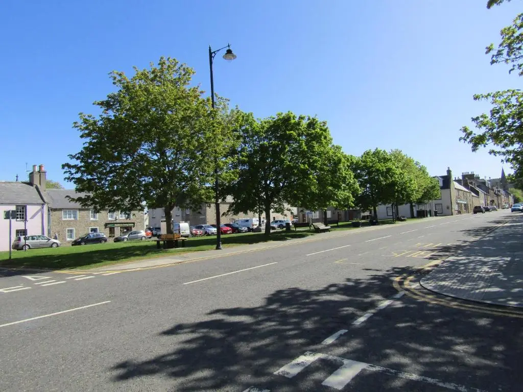 an empty street in a residential neighborhood with trees at The Red Lion Tavern in Fochabers