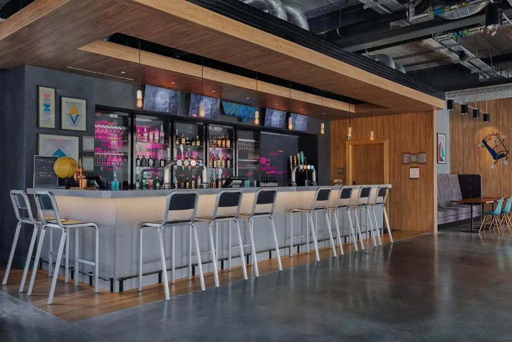 a bar with a row of stools in a room at Aloft Aberdeen TECA in Aberdeen