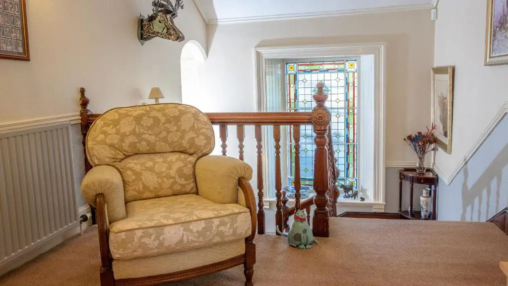 a living room with a chair and a stained glass window at Kiltearn Guest House in Evanton