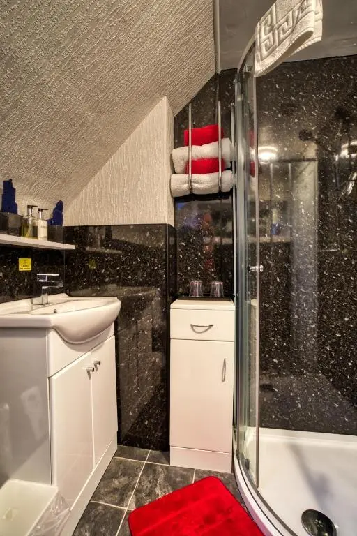 a bathroom with a shower and a sink and a tub at Pitfaranne Guest House in Inverness
