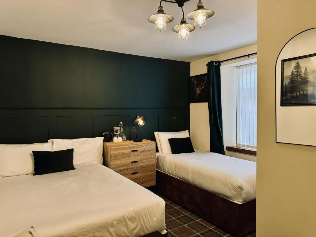 a bedroom with two beds and a green wall at Pitfaranne Guest House in Inverness