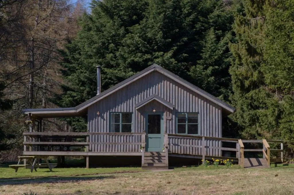 a small wooden cabin with a green door at Ben Macdui in Banchory