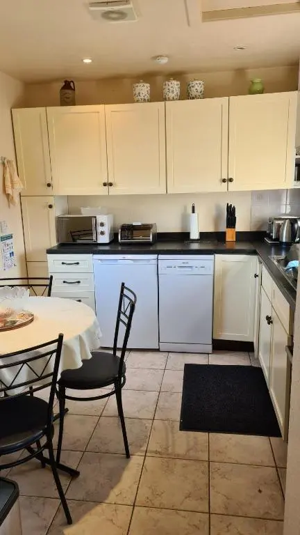 a kitchen with white cabinets and a table and chairs at Skye Cottage, Meadowside House, near Kingussie in Kingussie