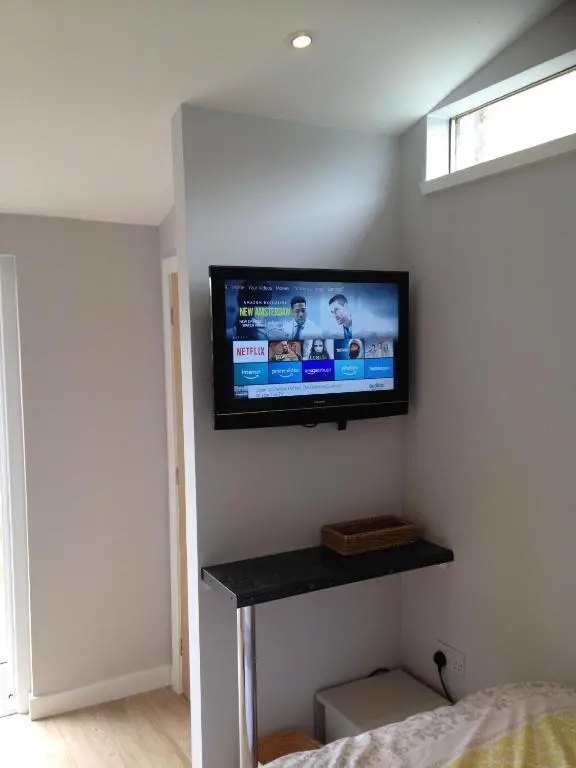 a flat screen tv on a wall in a bedroom at ensuite garden room in Inverness