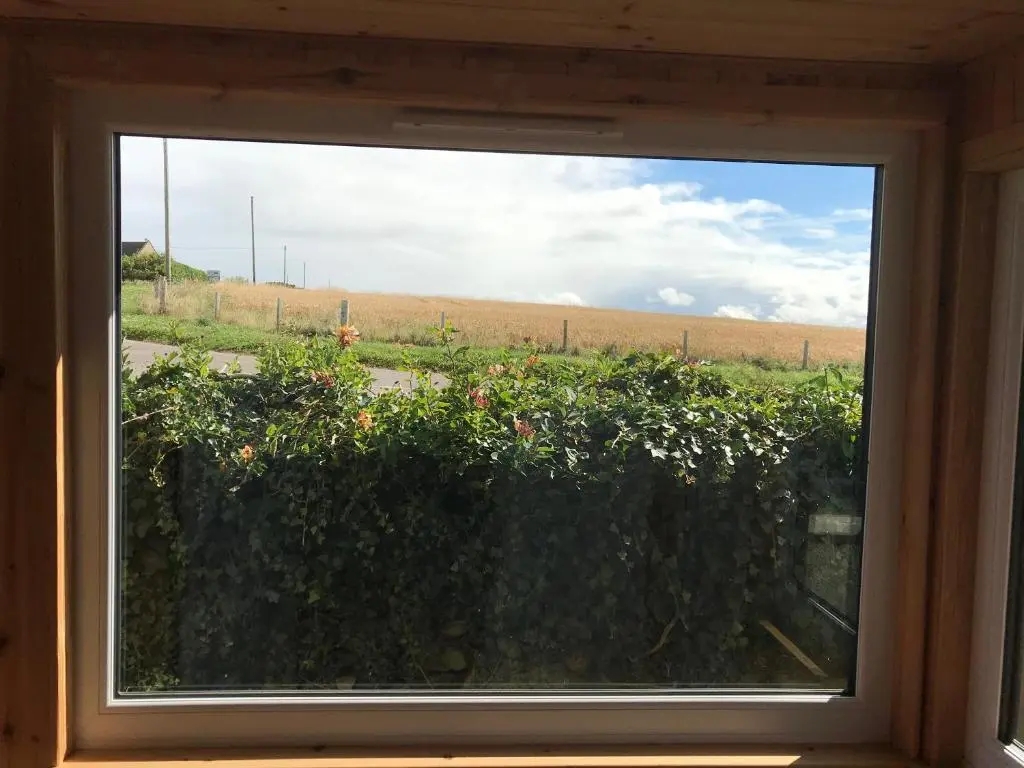 a window with a view of a field of flowers at Crossgates, Rosehearty in Rosehearty