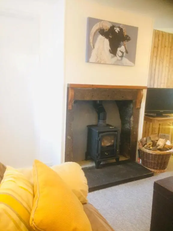 a living room with a fireplace with a horse picture on the wall at Crossgates, Rosehearty in Rosehearty