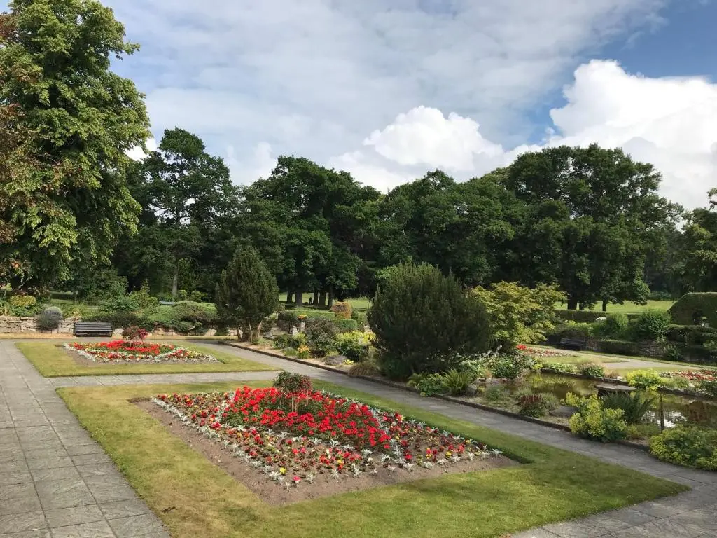 a garden with red flowers in a park at Exclusive Private double room, en-suite wet room Private entrance in Forres