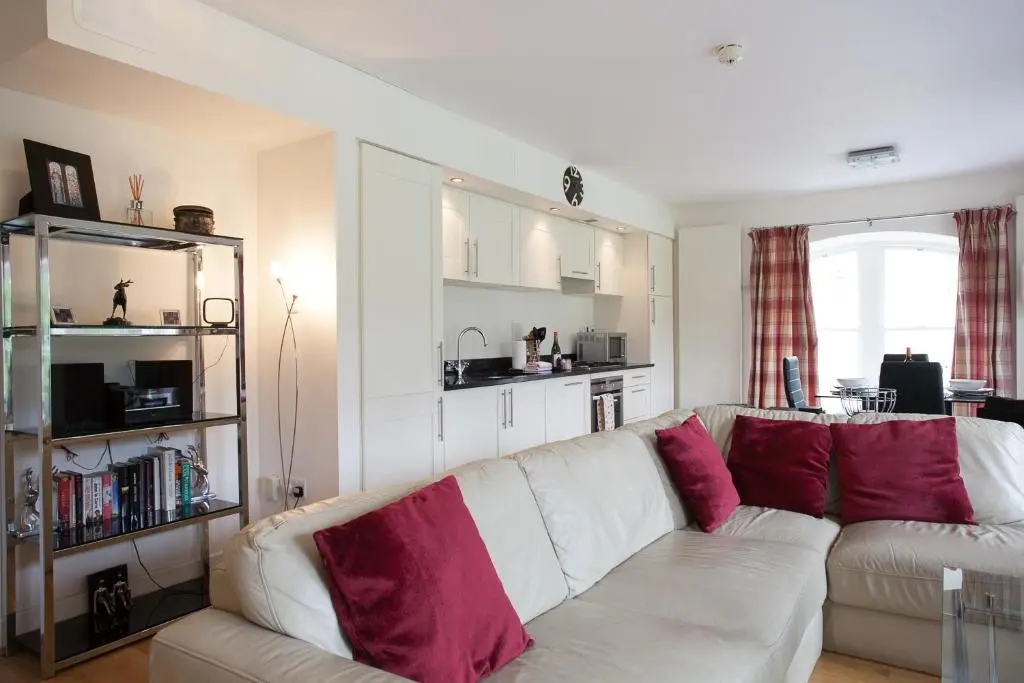 a living room with a white couch with red pillows at Old School 10 Apartment With A View in Fort Augustus