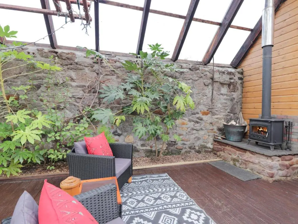 a patio with a stone wall and a stove at The Orangery in Turriff