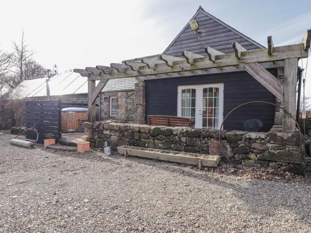 a small house with a stone wall and a pergola at The Orangery in Turriff