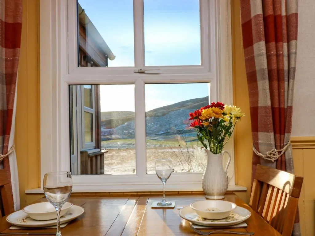 a table with a vase of flowers and a window at The Bothy in Kirriemuir