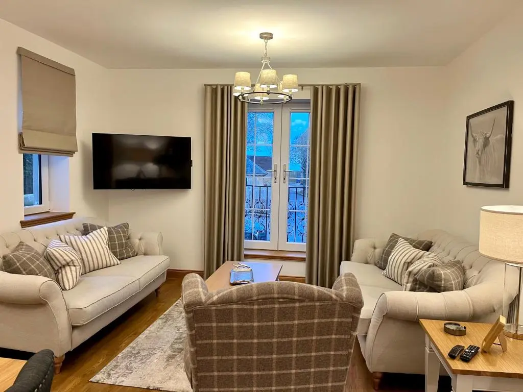 a living room with two couches and a tv at Royal Golf Apartments in Dornoch