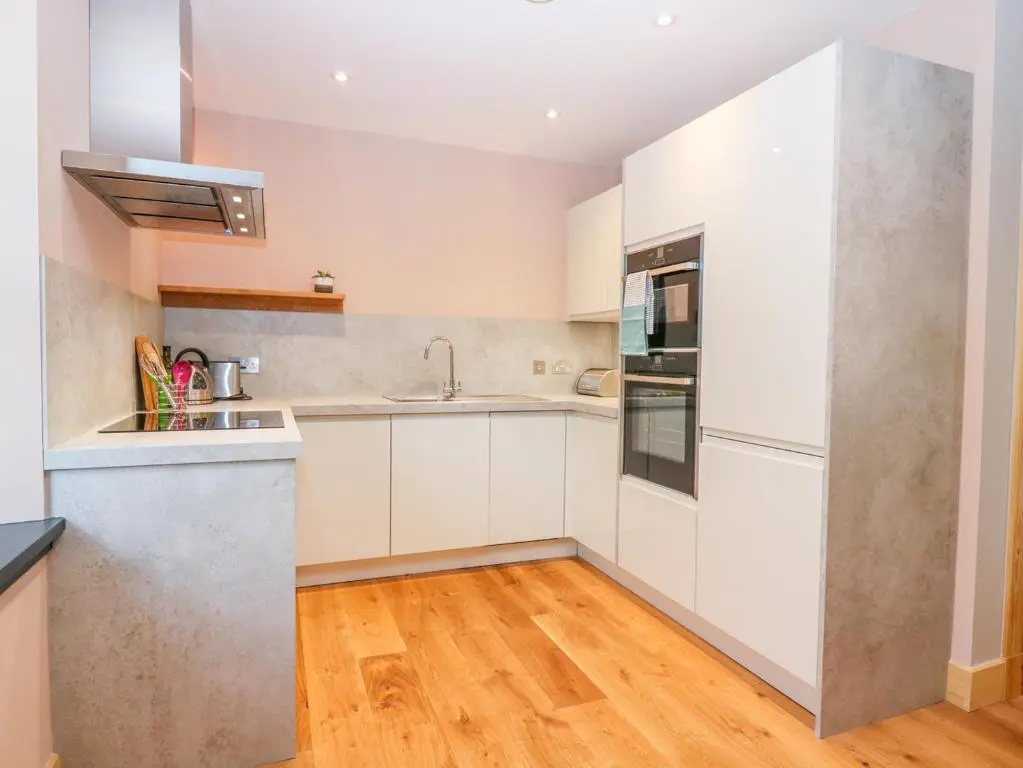 a kitchen with white cabinets and a wooden floor at Boat House in Invergarry