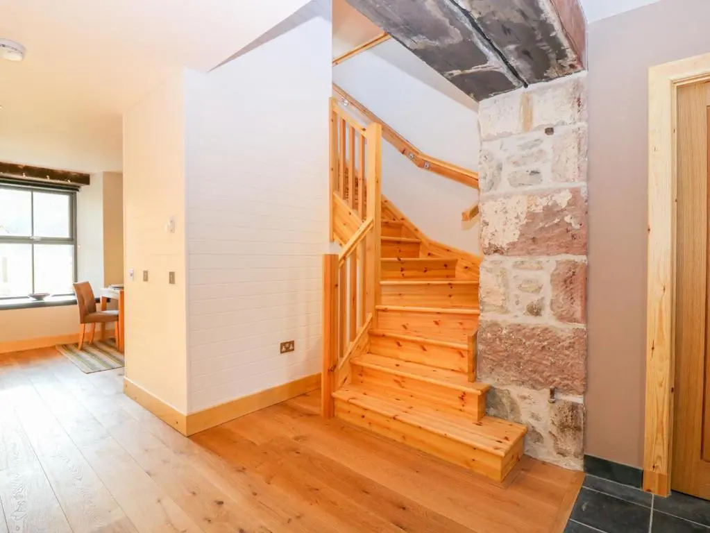 a hallway with a wooden staircase in a house at Boat House in Invergarry