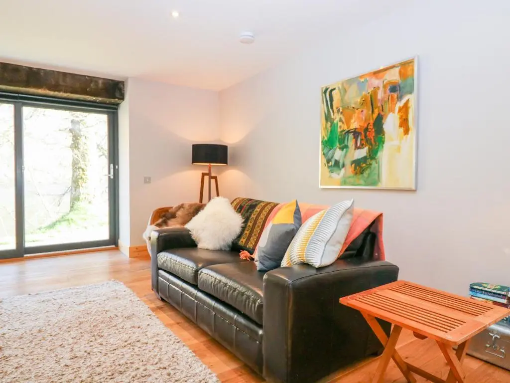 a living room with a black leather couch and a table at Boat House in Invergarry