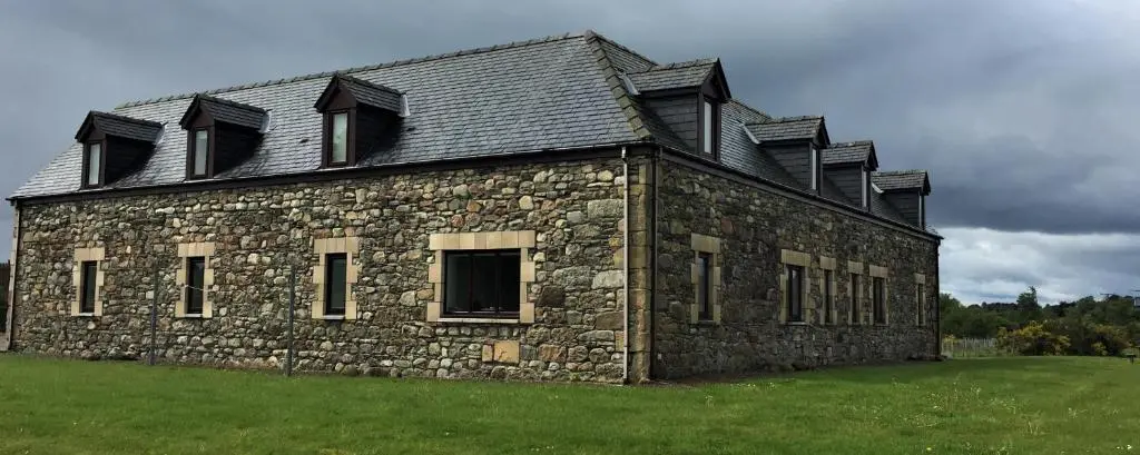 an old stone building with windows on a field at Heathfield Highland Estate in Invergordon