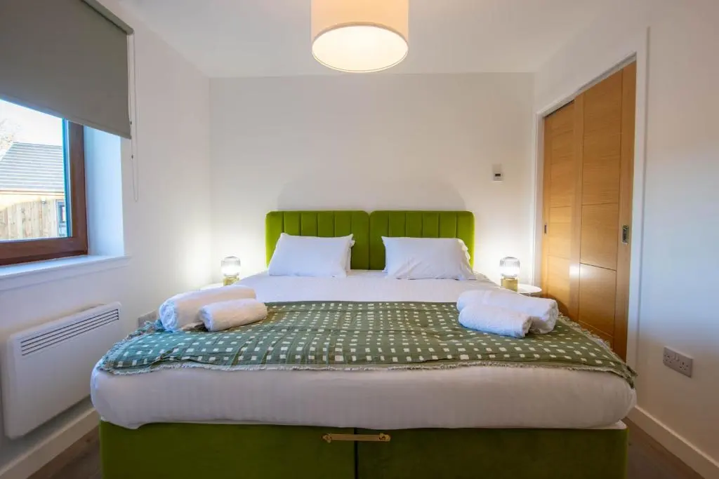 a bedroom with a large bed with a green headboard at Heathfield Highland Estate in Invergordon
