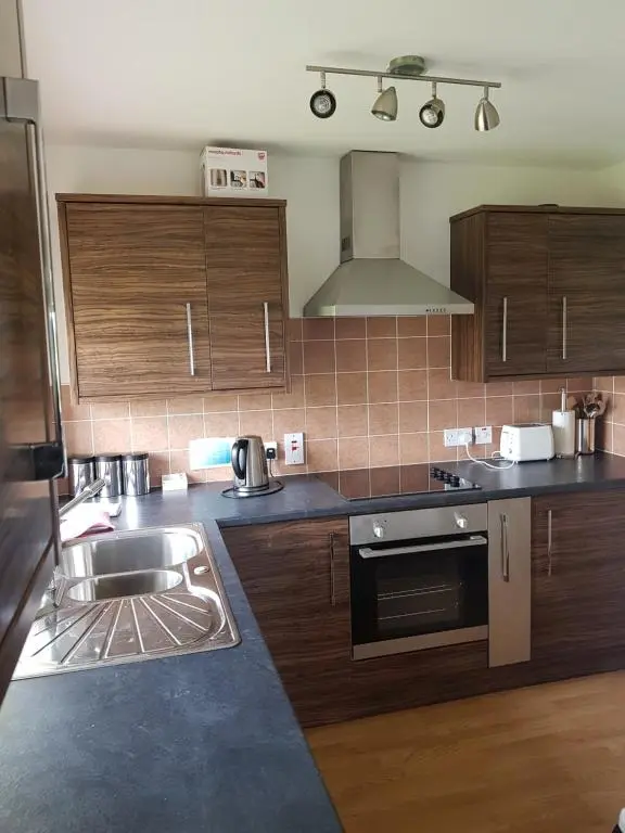 a kitchen with wooden cabinets and a sink at Heathfield Highland Estate in Invergordon