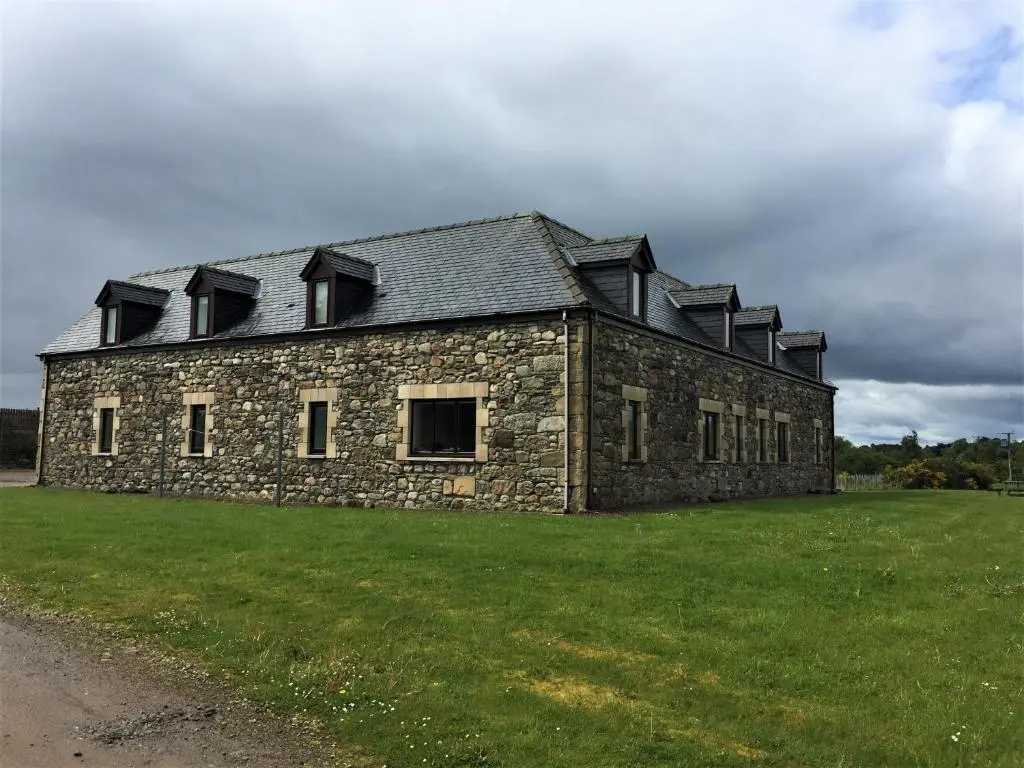 a stone building with a roof on a field at Heathfield Highland Estate in Invergordon