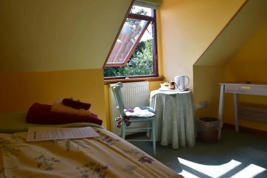 a bedroom with a bed and a window and a chair at Sunflower Bed & Breakfast in Findhorn