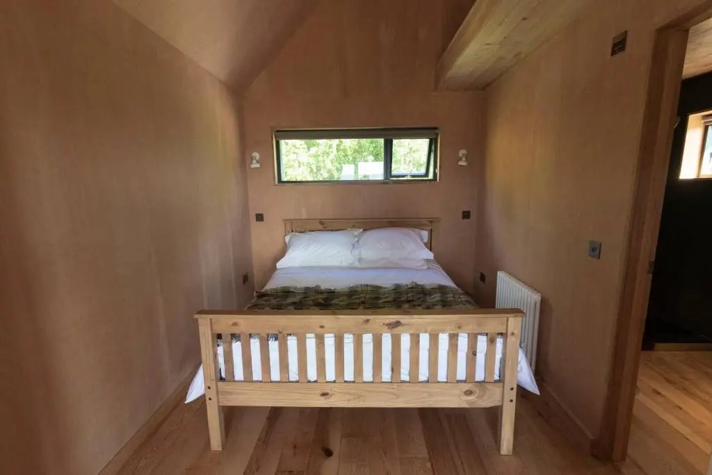 a bed in a small room with a window at Birdwatcher's Cabin in Golspie