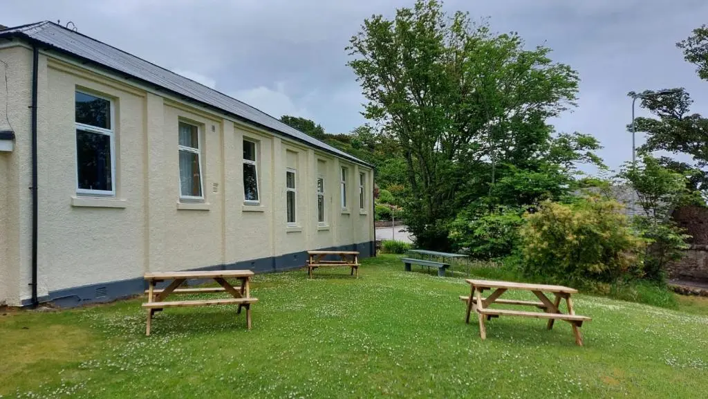 two benches sitting in the grass next to a building at Helmsdale Lodge Hostel - all rooms en-suite in Helmsdale