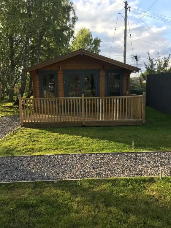 a log cabin with a porch and a fence at Star Cabin Lairg in Lairg