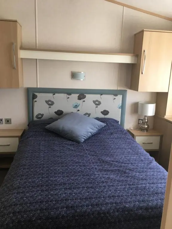 a bedroom with a bed with a blue comforter at 87 Lighthouse View Lodge in Lossiemouth