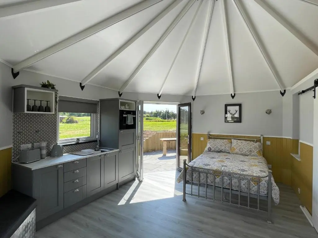 a room with a bed and a kitchen in a tent at AC/DC Glamping in New Aberdour