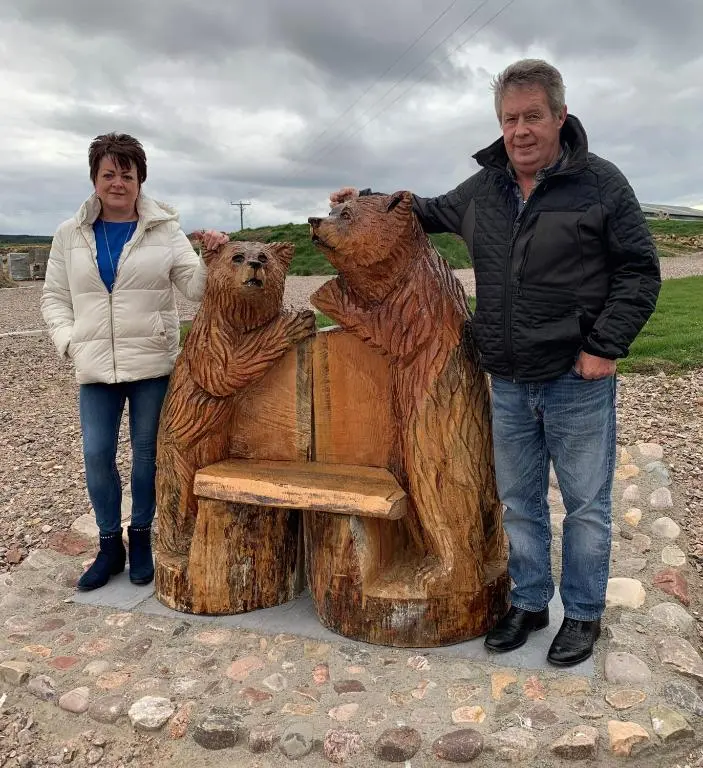 a man and a woman standing next to a bear bench at AC/DC Glamping in New Aberdour