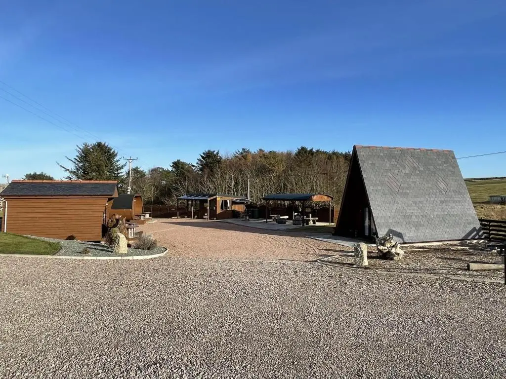 a building with a black roof on a gravel road at AC/DC Glamping in New Aberdour