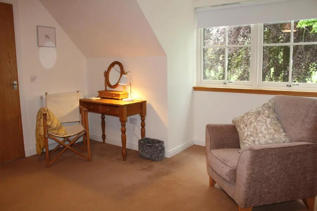 a living room with a chair and a table with a mirror at Roualeyn in Huntly
