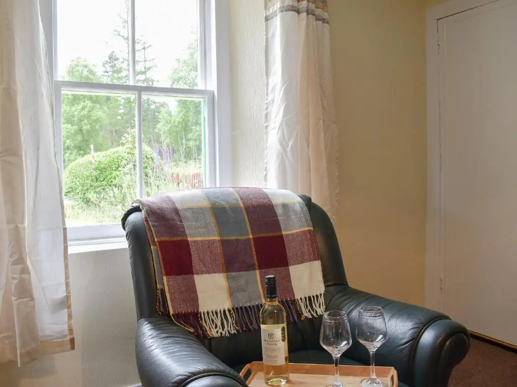 a leather chair with a blanket and two wine glasses at Ben View in Orbliston