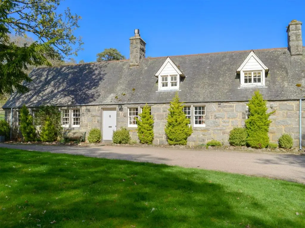 an old stone house with trees in front of it at Tressady Coach House in West Langwell
