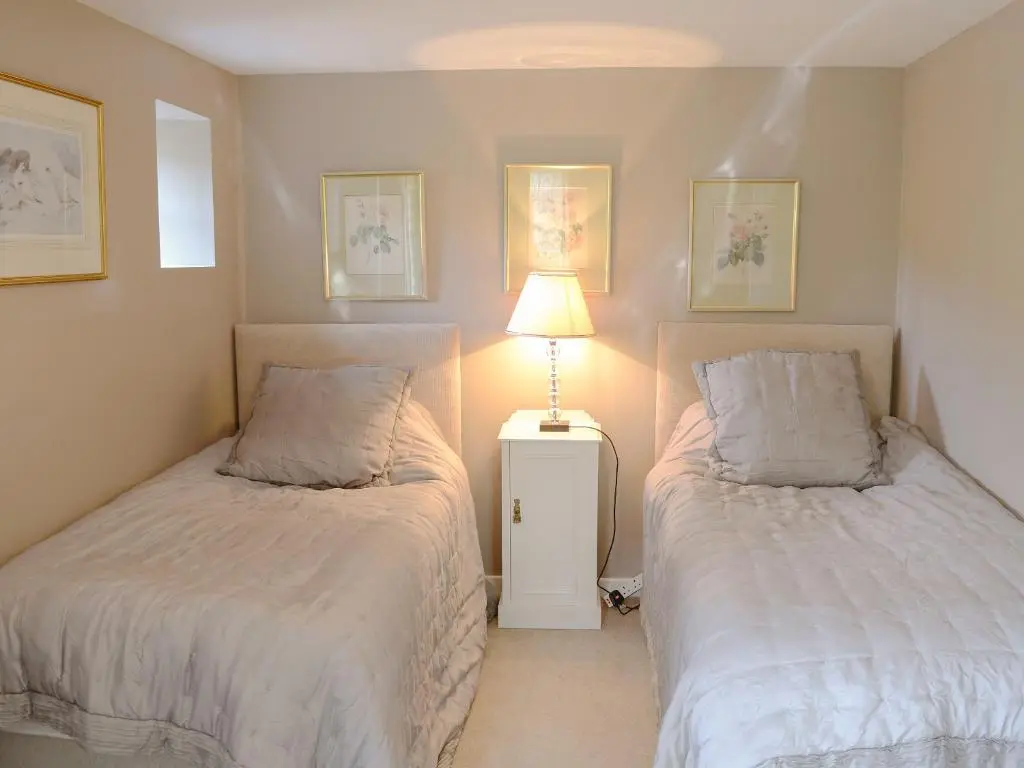 a bedroom with two beds and a lamp on a table at Tressady Coach House in West Langwell