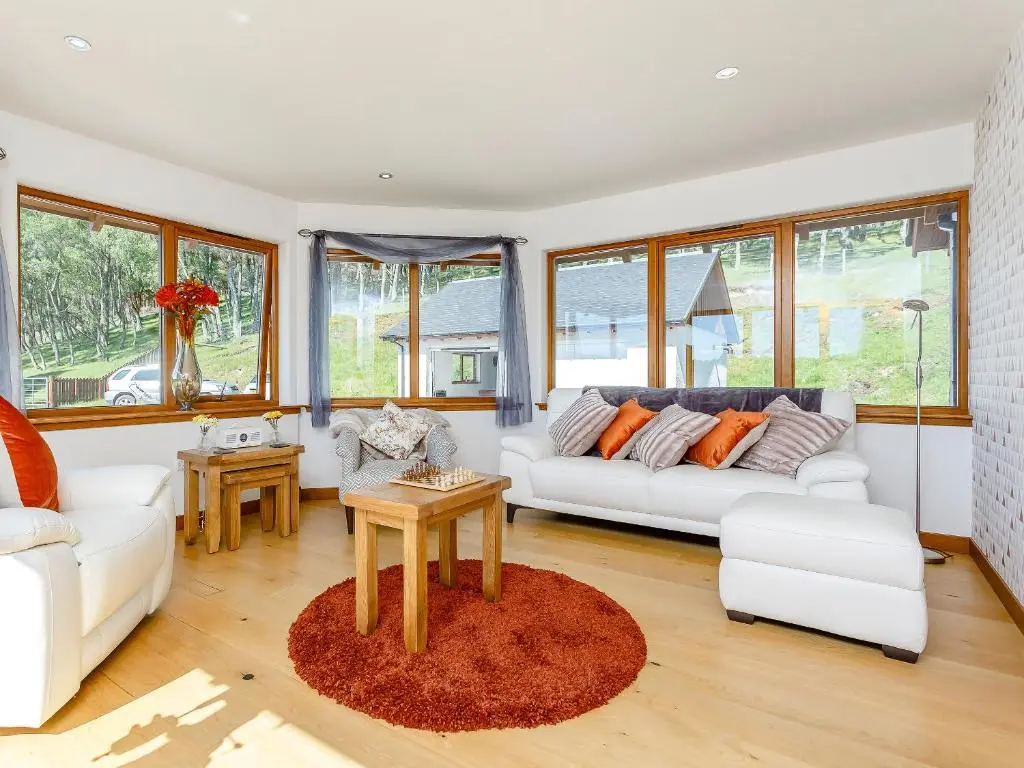 a living room with two white couches and a table at Sunnyside House in Duthil