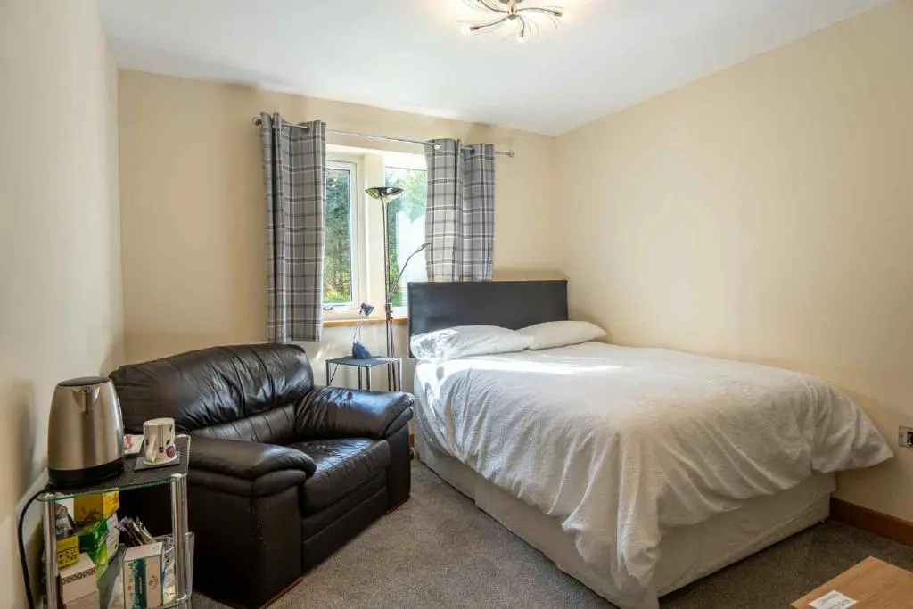 a bedroom with a bed and a leather chair at Drumlochy B&B in Inverness