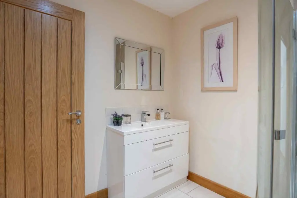 a bathroom with a white sink and a mirror at Drumlochy B&B in Inverness